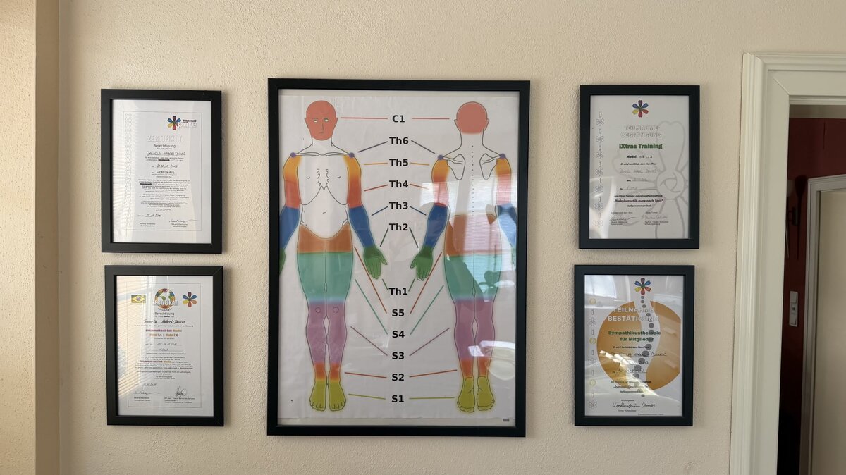 Ausbildungsnachweise und Wirbelsäulen-Übersicht im Behandlungsraum